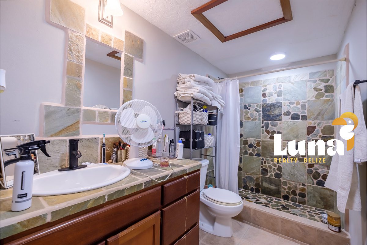 Modern bathroom with stone-tiled shower area.