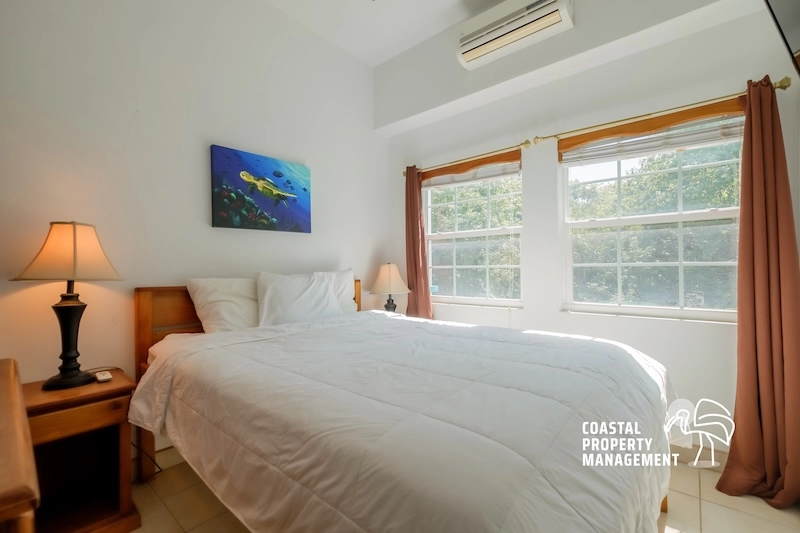 Bright bedroom with bed and large windows.
