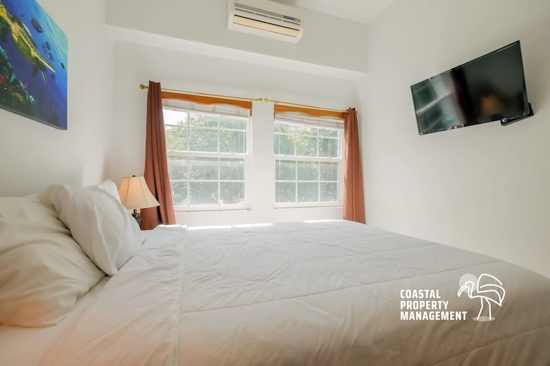 Bright bedroom with bed and mounted TV.