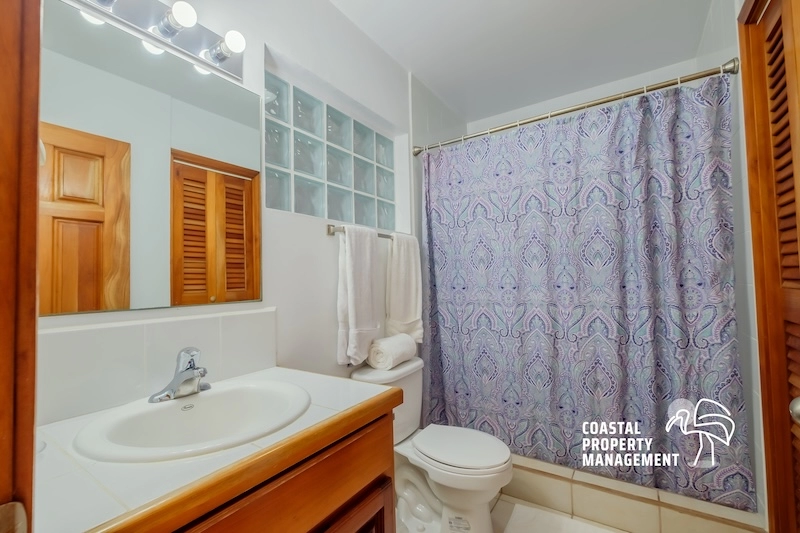 Bathroom with shower curtain and wooden cabinets.