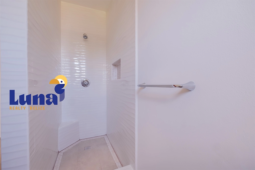 White tiled shower with towel holder.