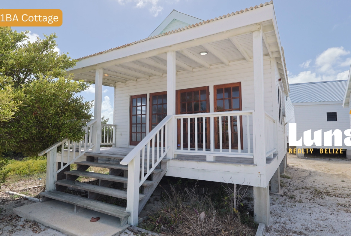 White cottage with wooden porch and stairs.