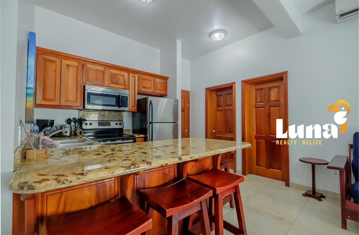 Modern kitchen with wooden cabinets and stools.