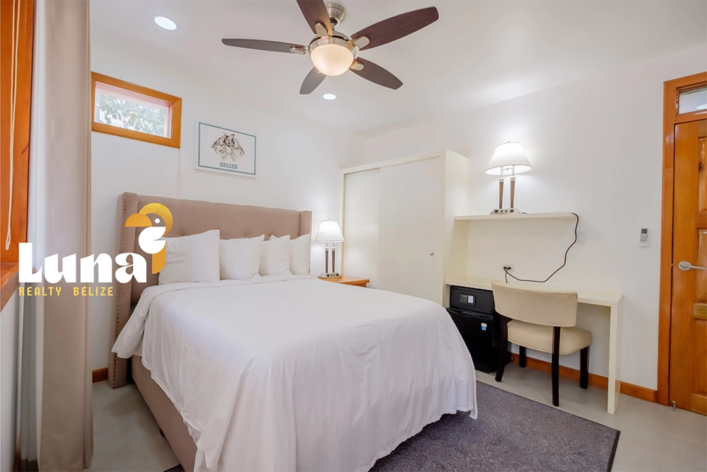 Cozy bedroom with bed, desk, and lamp.