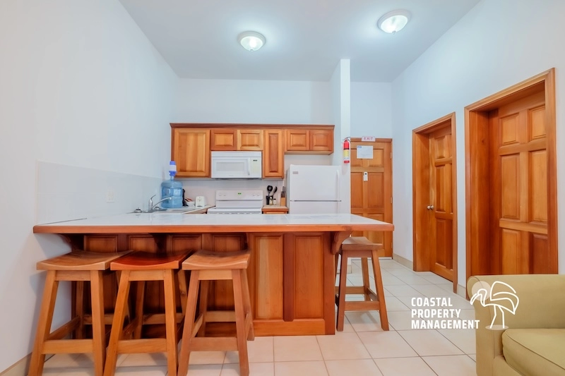 Wooden kitchen with bar stools and appliances.