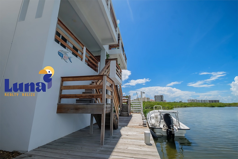 House by water with small docked boat.