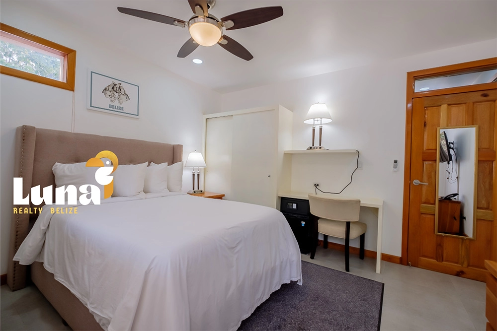 Modern bedroom with bed, desk, and fan.
