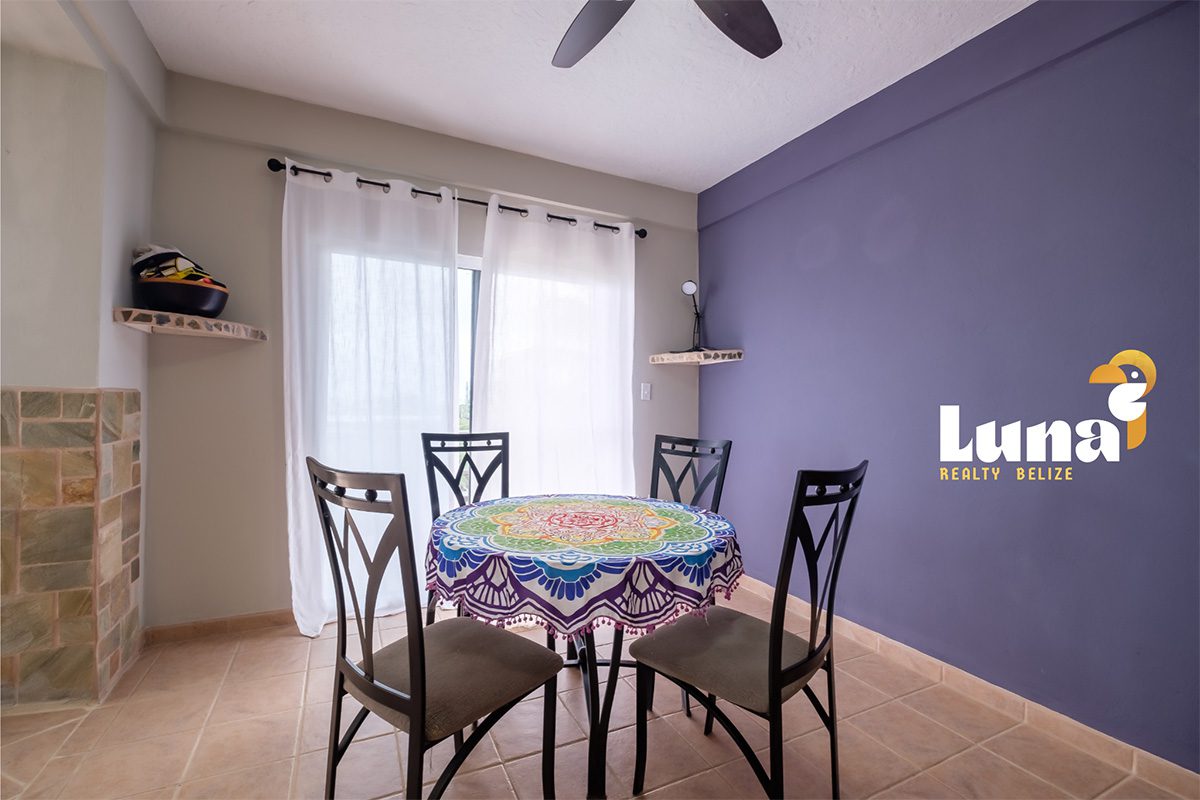 Dining area with colorful tablecloth and chairs.