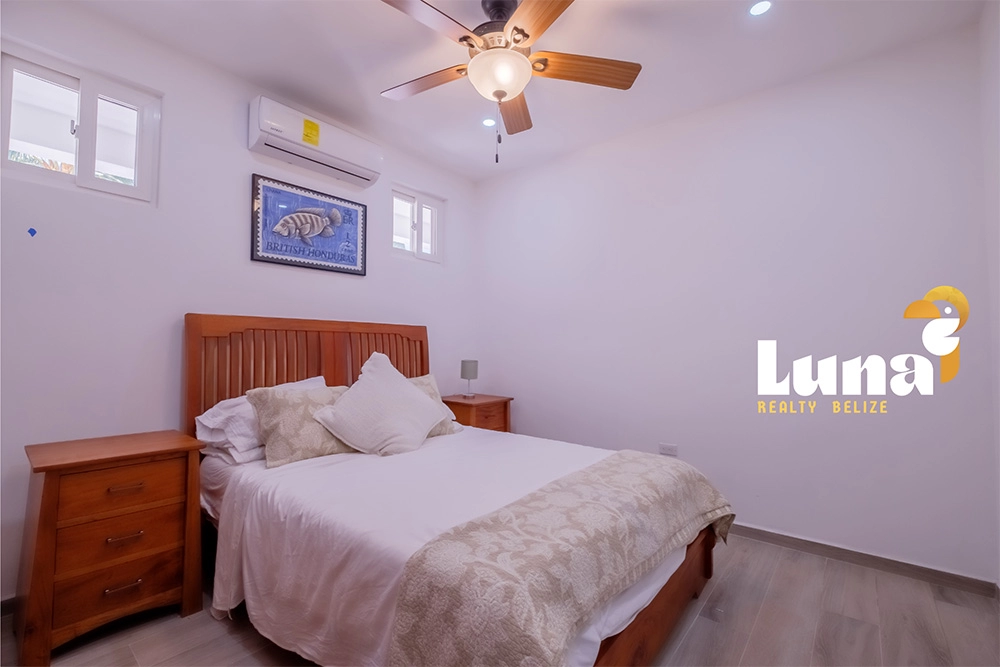 Bedroom with bed, ceiling fan, and artwork.