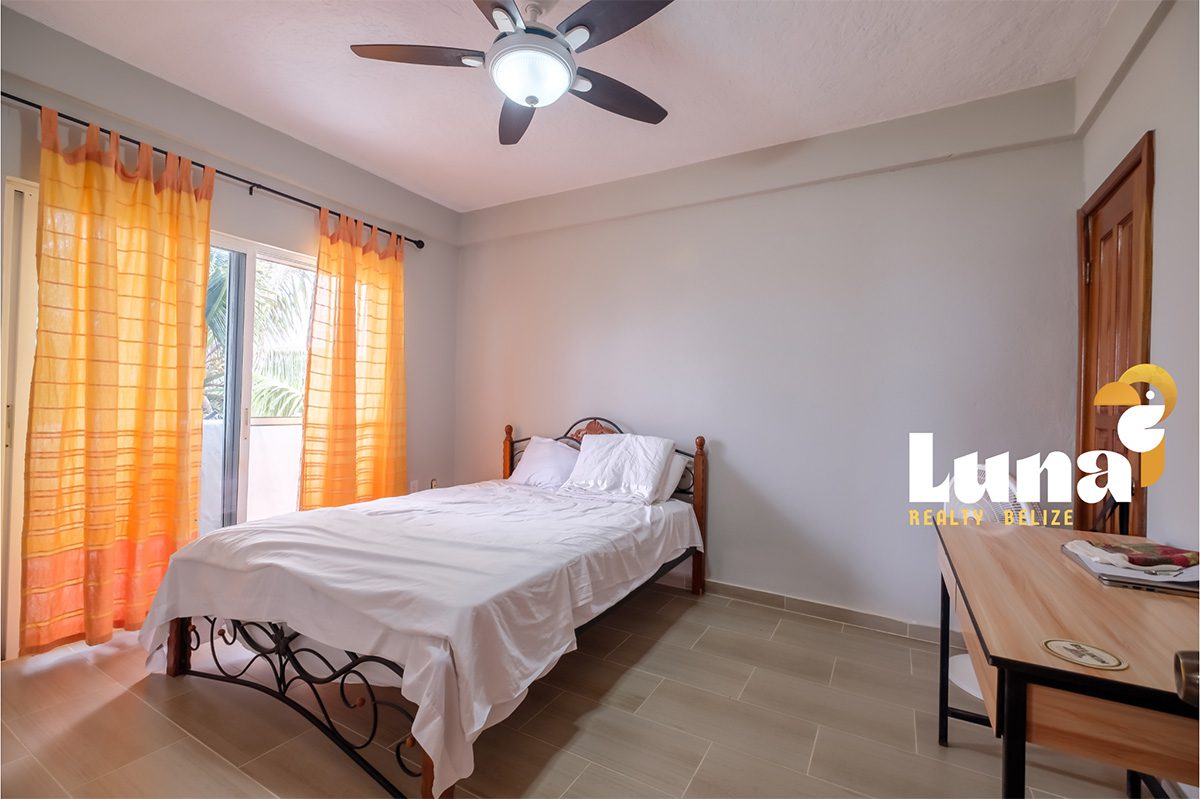 Bedroom with orange curtains and ceiling fan.