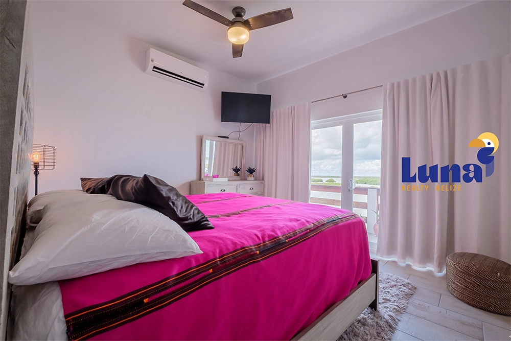 Bedroom with pink bedding and balcony view.