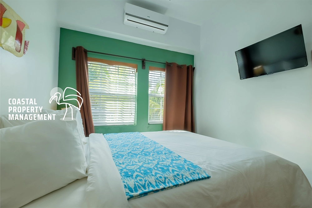 Bedroom with bed, TV, and window blinds.