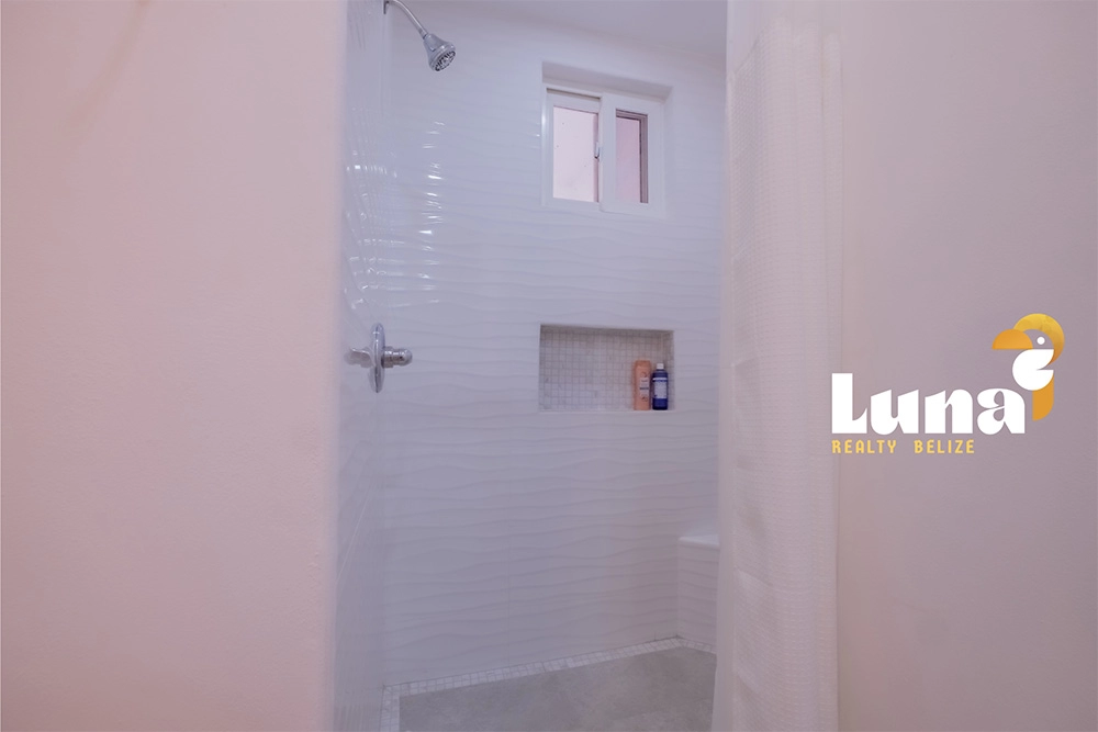 Modern white tiled shower with window.