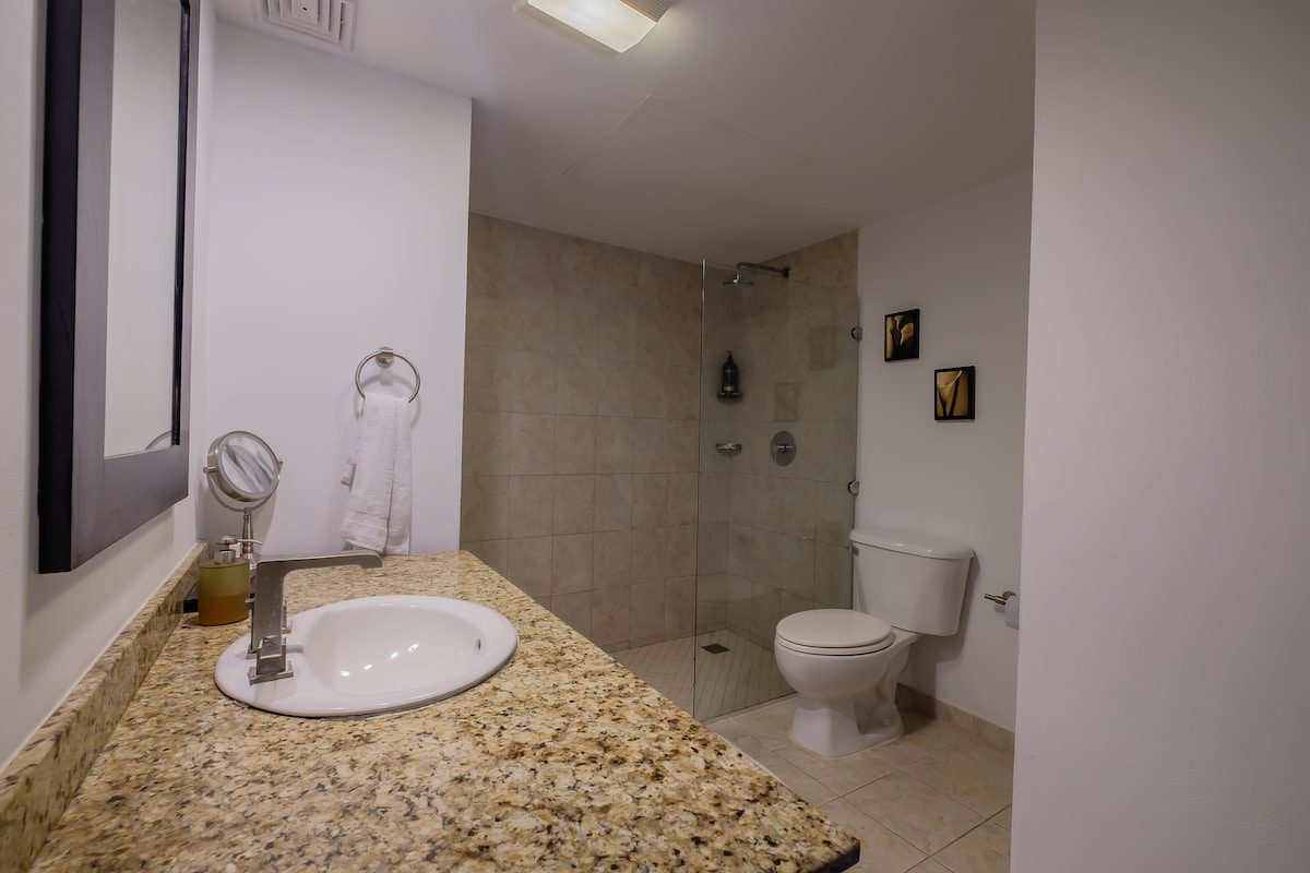 Modern bathroom with granite countertop and shower.