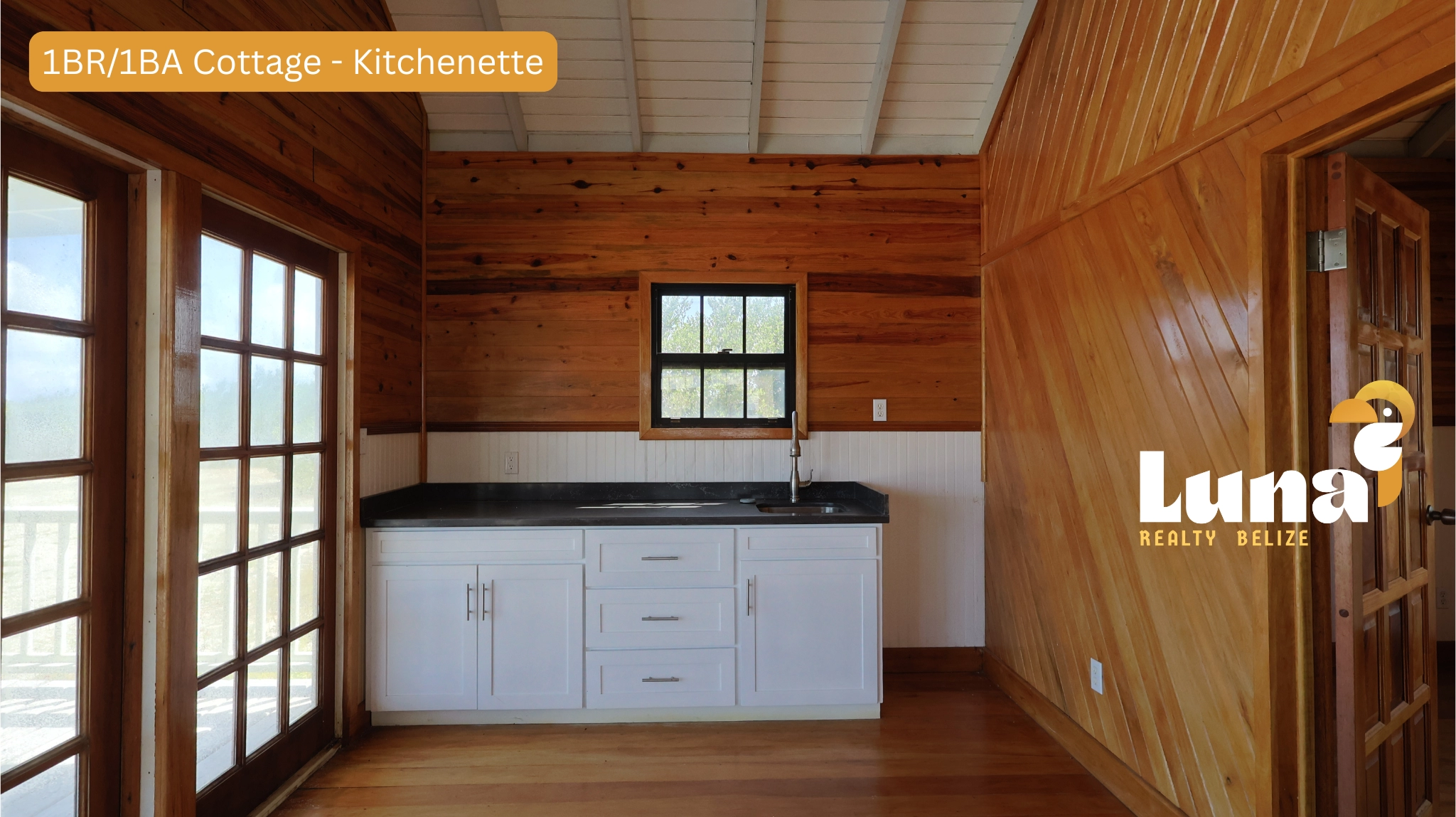 Wooden kitchenette with window and white cabinets.