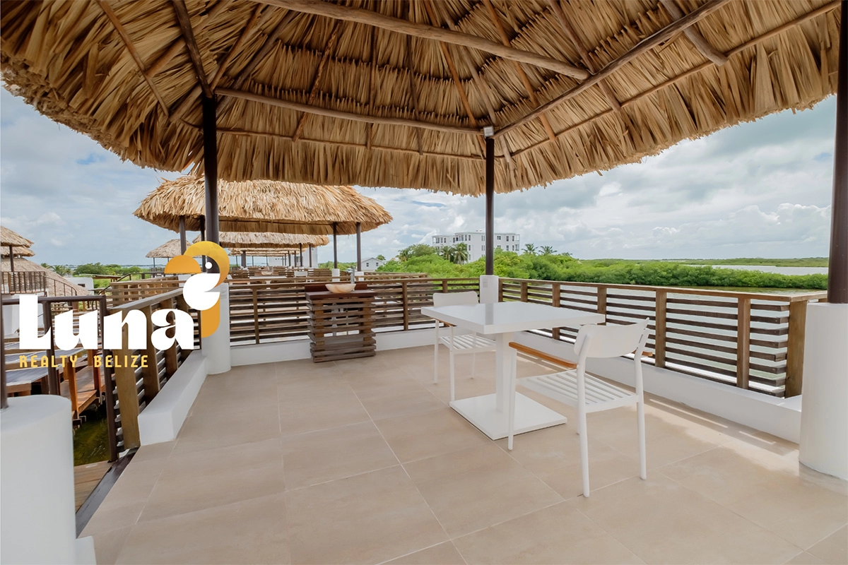 Outdoor terrace with thatched roof and chairs.