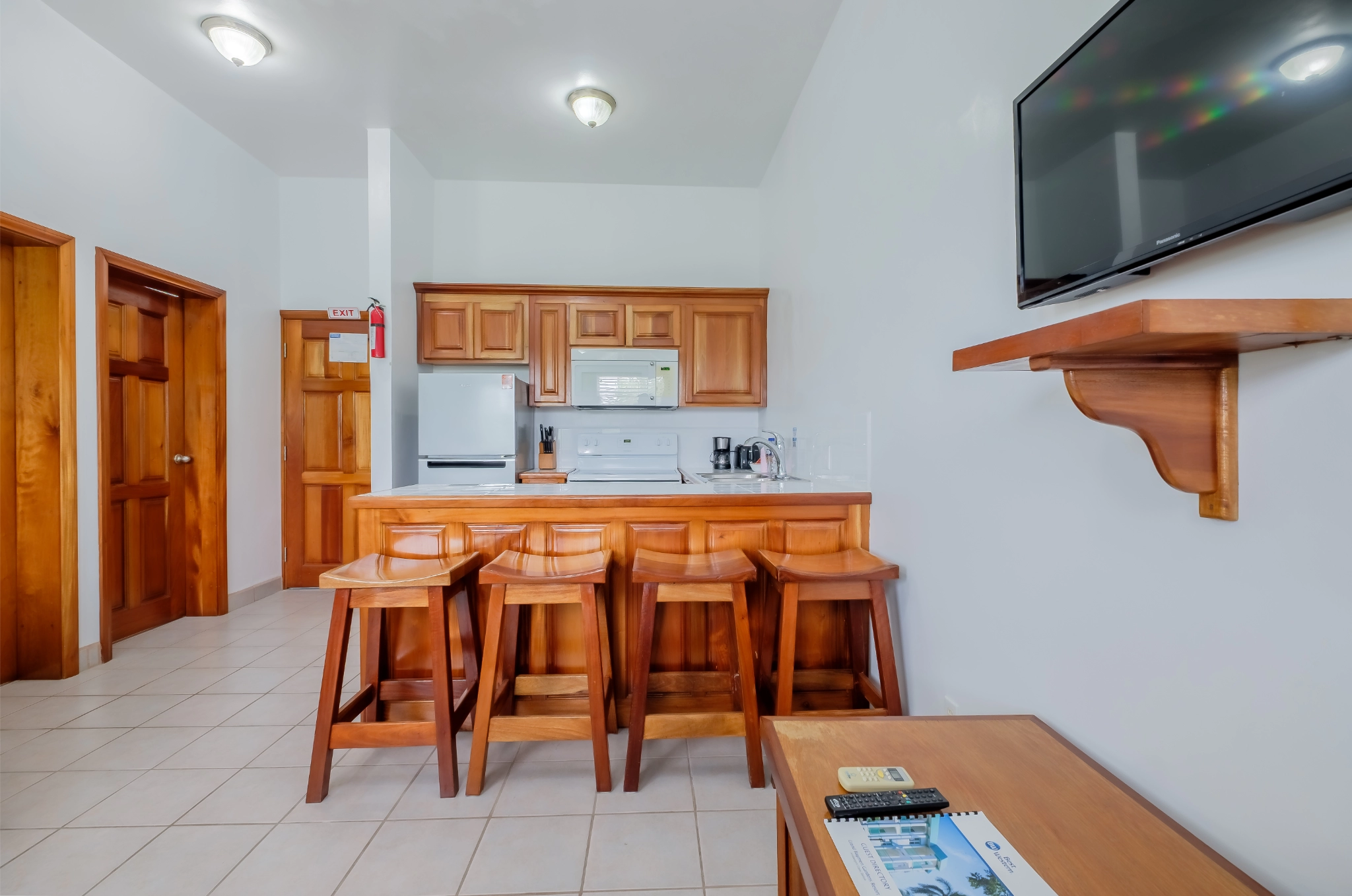 Wooden kitchen with bar stools and TV.